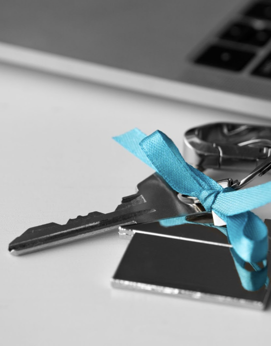 Close-up of a house key with a teal ribbon, a successful real estate transaction, and creative ways to attract new clients.